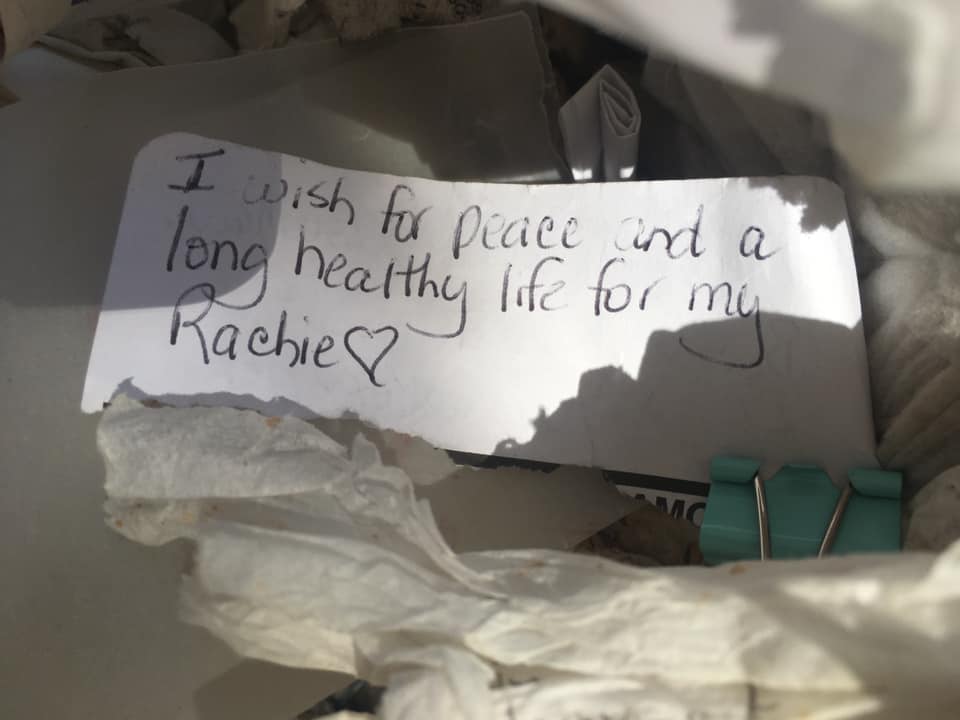 Handwritten prayer note reading 'I wish for peace and a long healthy life' on the wishing wall