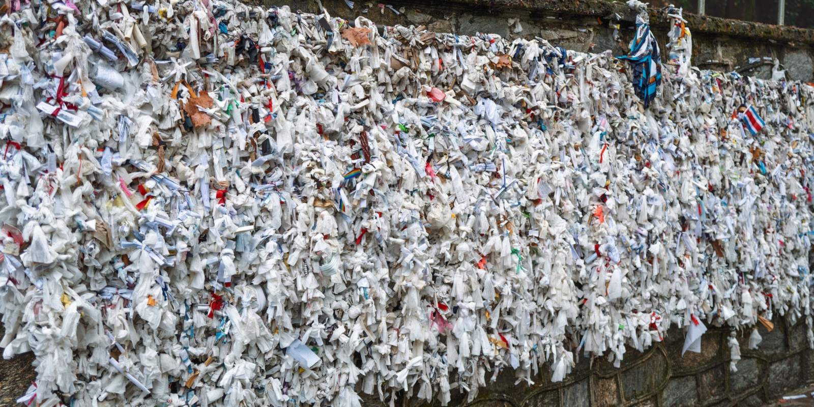 Thousands of folded paper and cloth prayers tied along the wishing wall