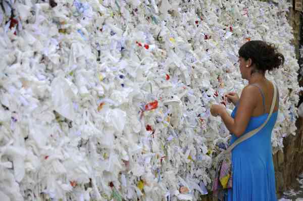 A visitor placing her written prayer on the wishing wall at the House of Virgin Mary